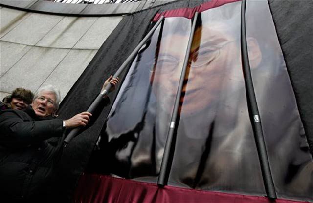 Near the U.N., Richard Gere removes symbolic prison bars from in front of a photograph of Liu